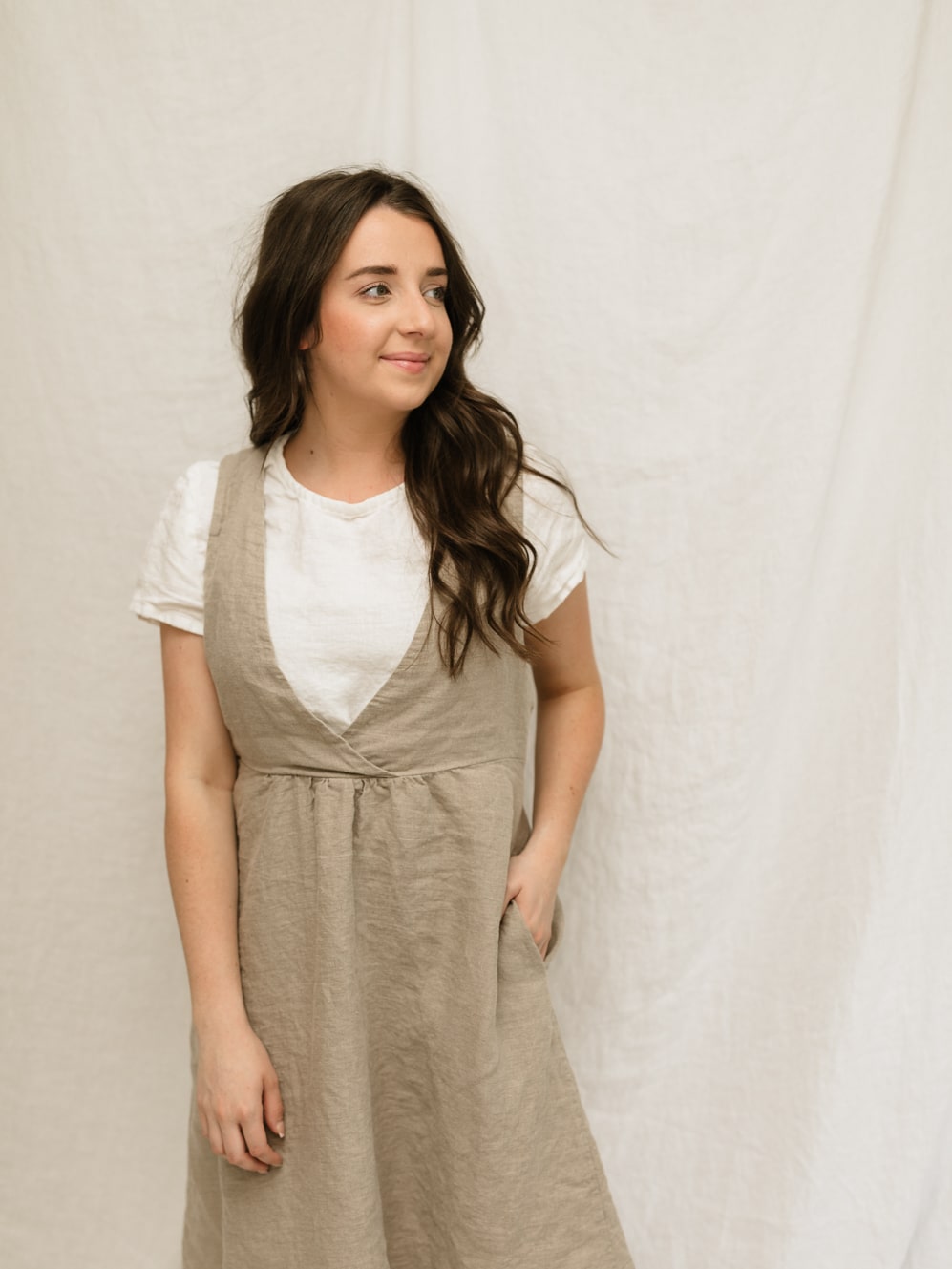 The Asa jumper features a crossed front bodice and plain back. The top of the dress is doubled for a clean finish and added durability. The gathered skirt includes hidden side seam pockets. Perfect for the sustainable closet. Made with quality linen. Customizable sizes.