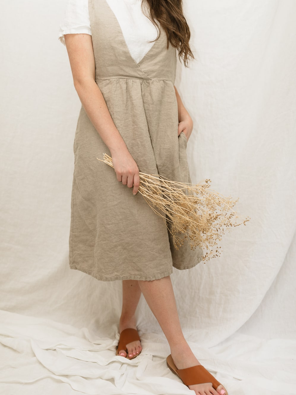 The Asa jumper features a crossed front bodice and plain back. The top of the dress is doubled for a clean finish and added durability. The gathered skirt includes hidden side seam pockets. Perfect for the sustainable closet. Made with quality linen. Customizable sizes.